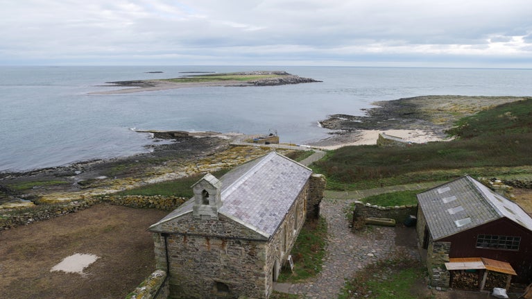 View of St Cuthbert's chapel from above, with the sea beyond.